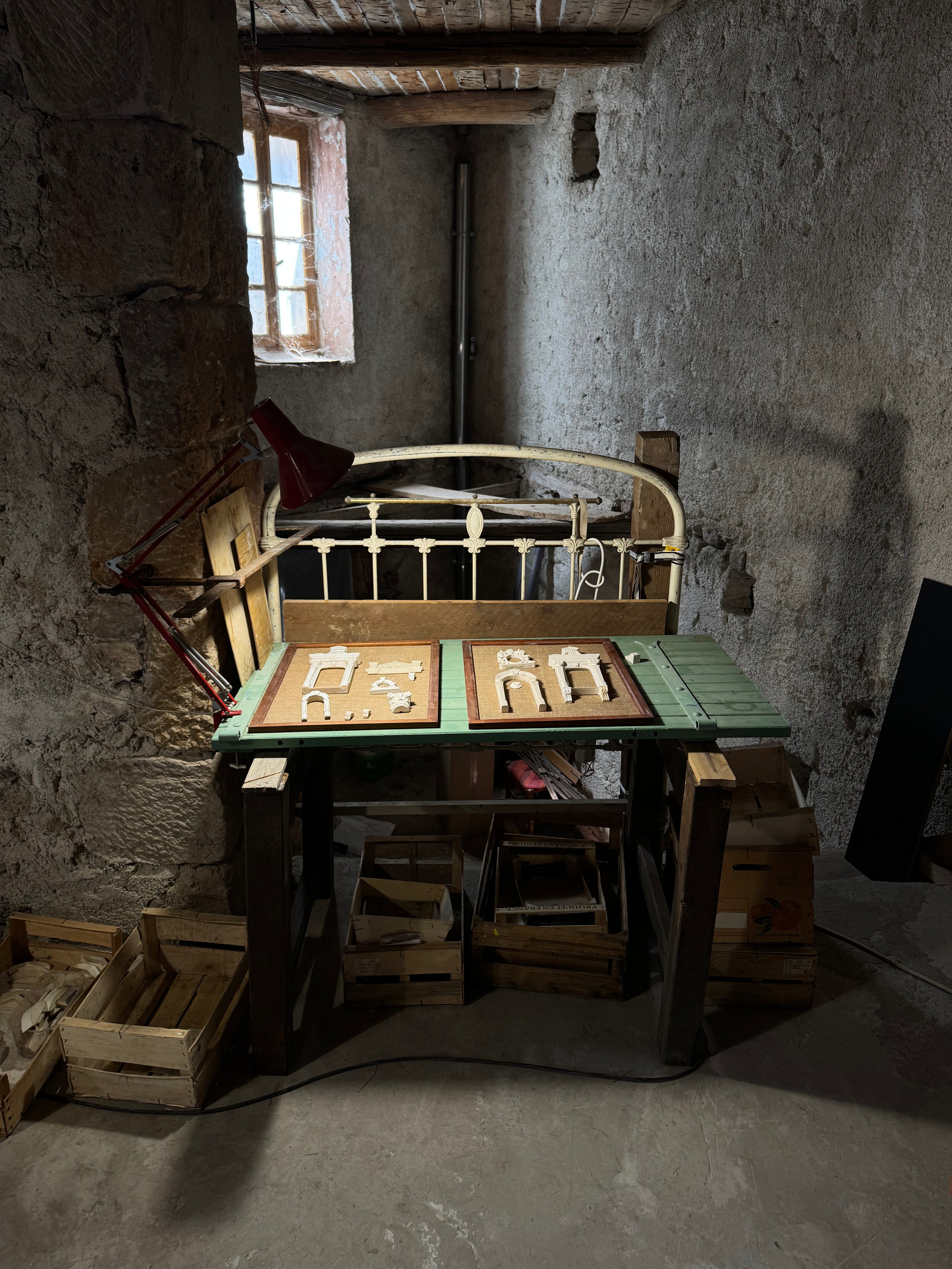 Two Architectural Archive panels in progress with hand-cast plaster reliefs on a green worktable inside Lansdown Arts’ stone studio in Gabian, France