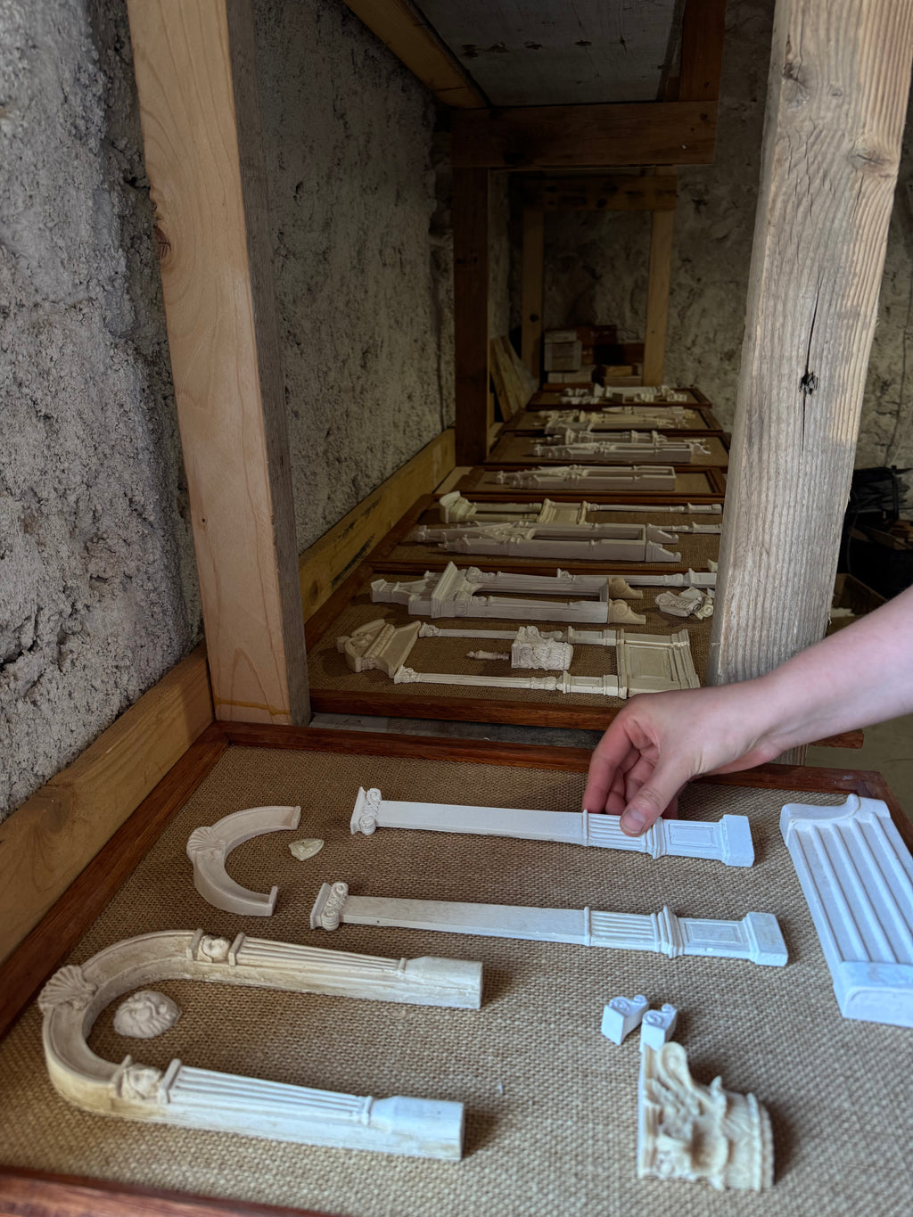 Apprentice placing long plaster columns and carved brackets onto hessian as multiple Architectural Archive panels are assembled in the Lansdown studio