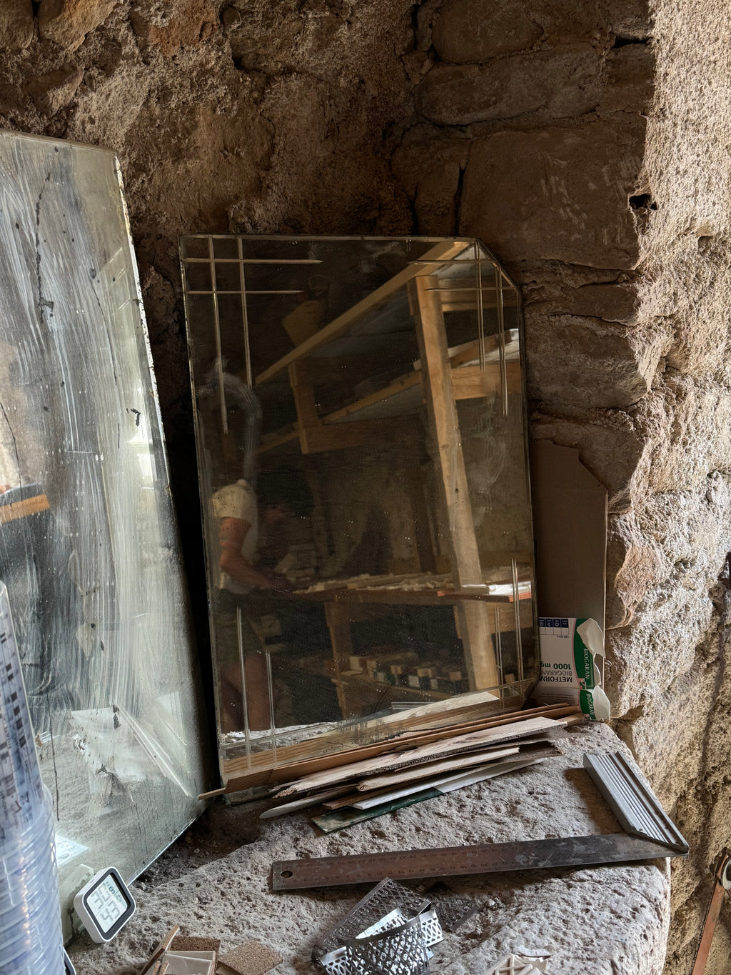 Bevelled rectangular mirror reflecting the Lansdown Arts workshop and a maker at work, surrounded by wood offcuts and hand tools in Gabian, France