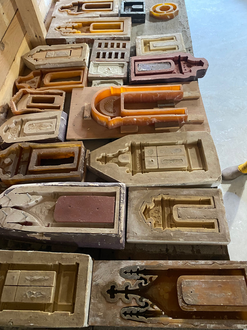 Miniature architectural casting moulds for doors, windows and carved ornaments arranged on a workbench in Eric Lansdown’s French studio
