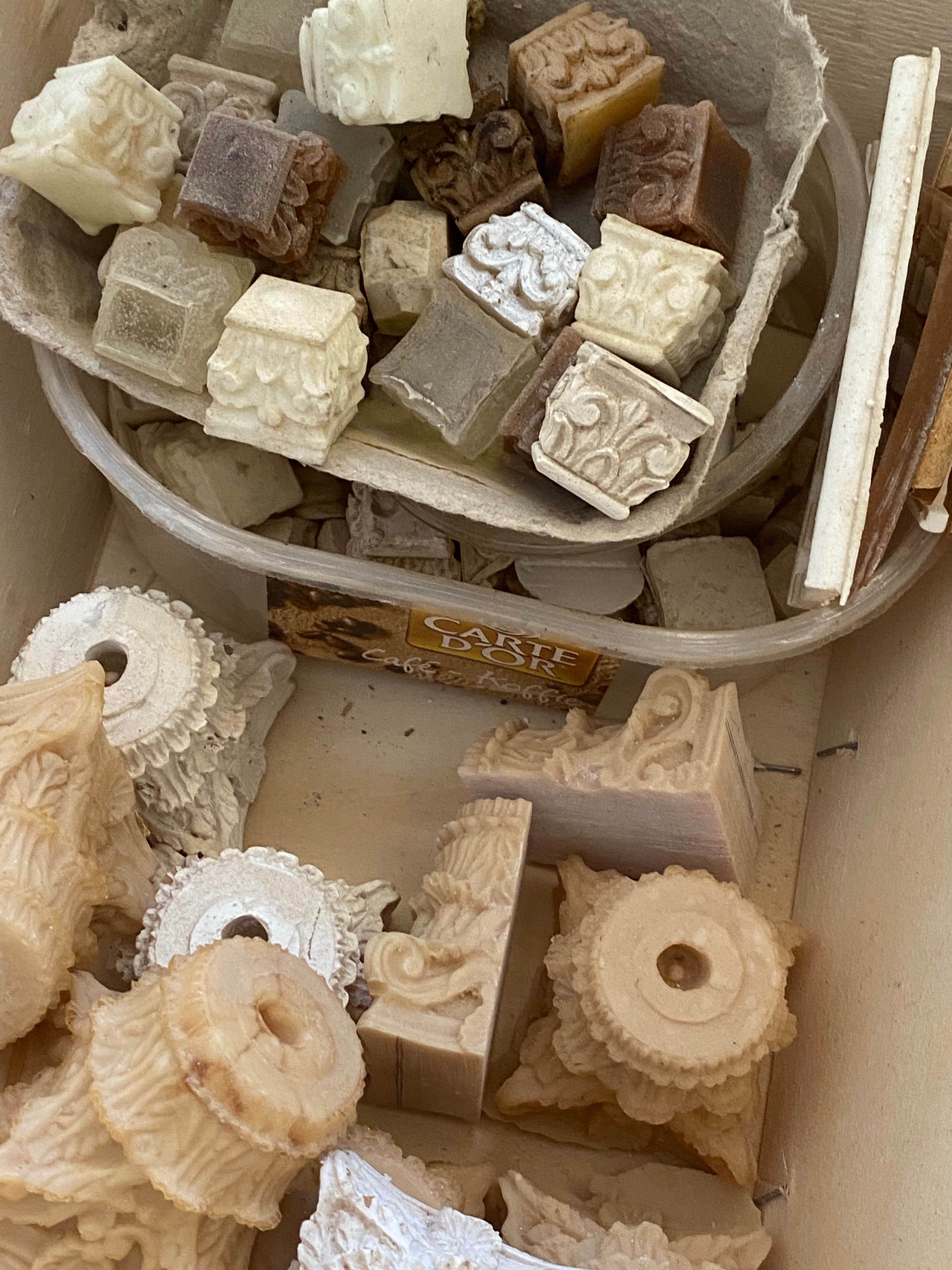 Archive of hand-cast plaster and resin architectural ornaments, including miniature capitals and rosettes, stored in Eric Lansdown’s workshop